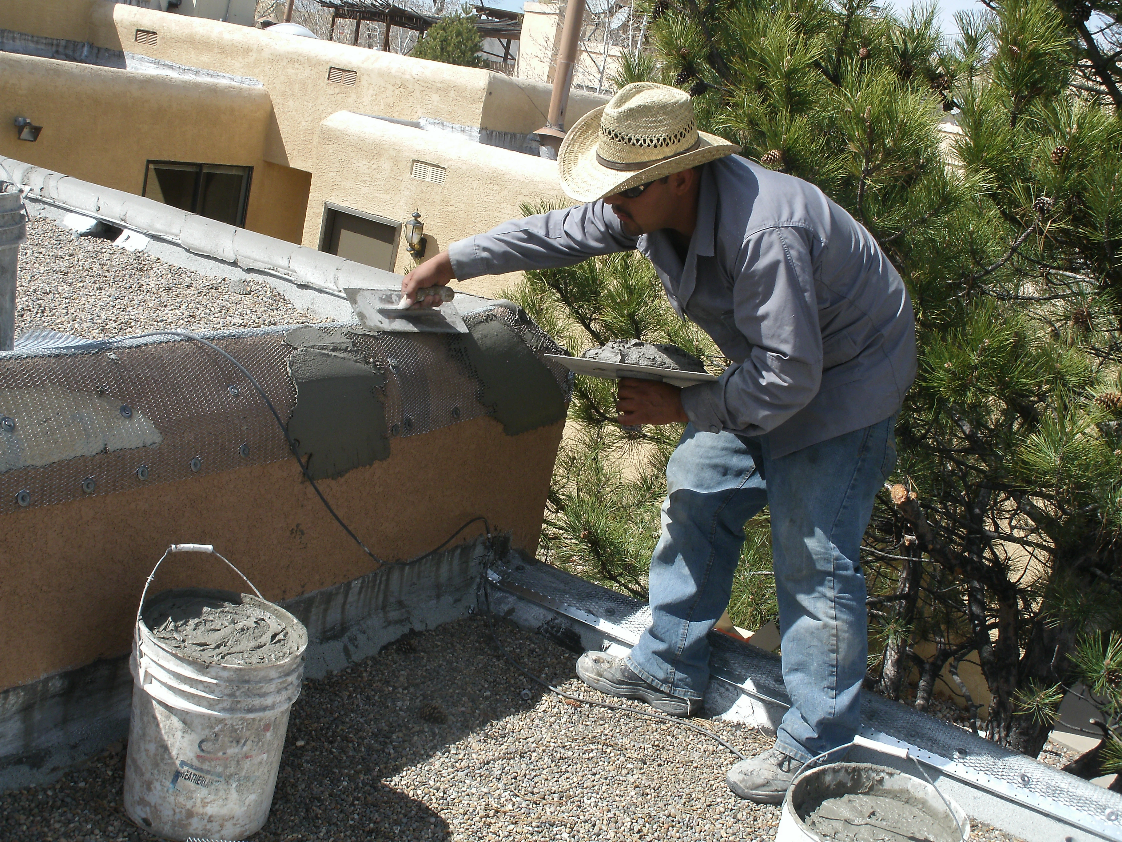 A man diligently applies cement to a wall, showcasing his craftsmanship and focus on construction work.