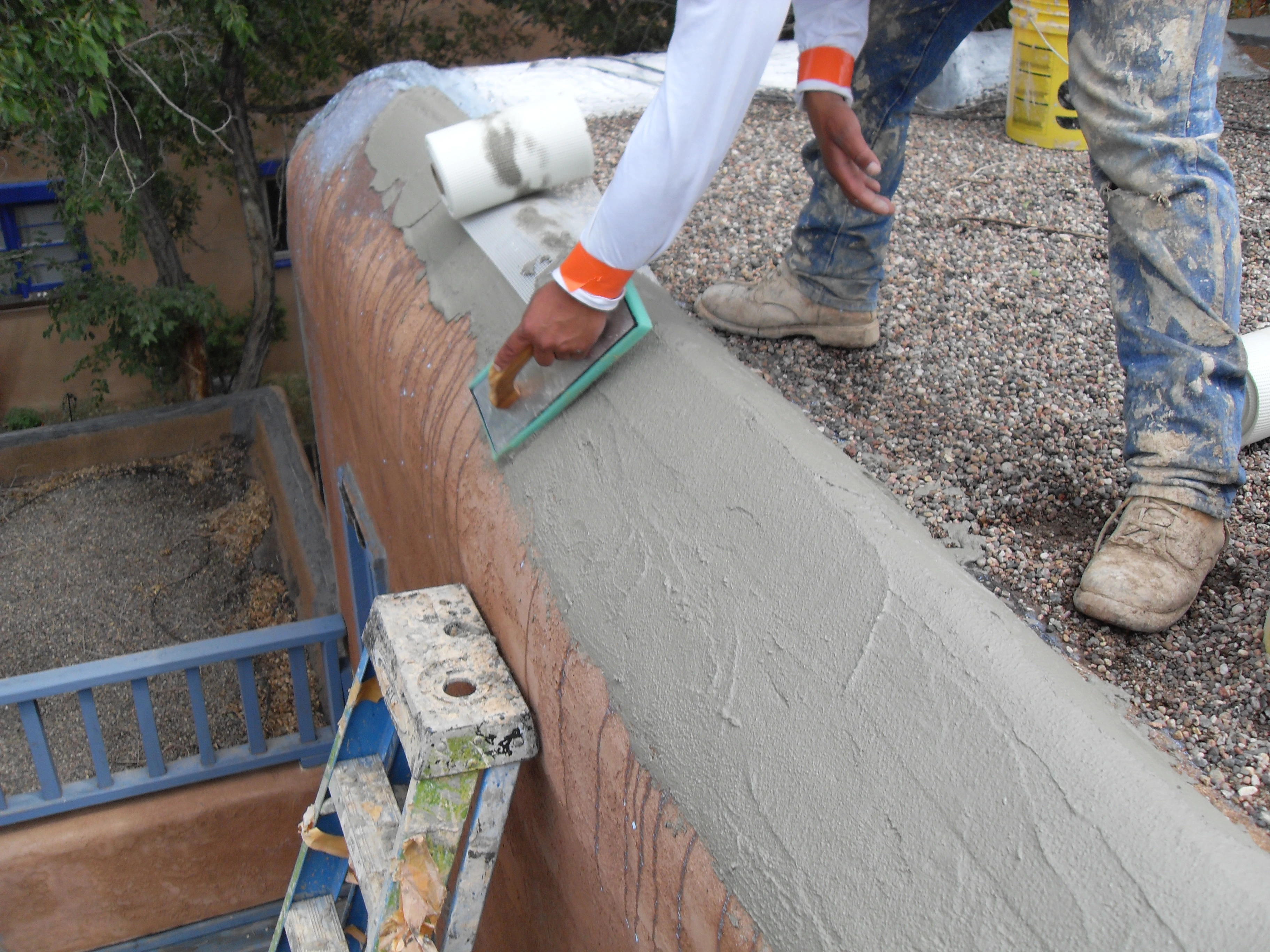 A man applies paint to a cement wall, showcasing his artistic skills and dedication to the task at hand.