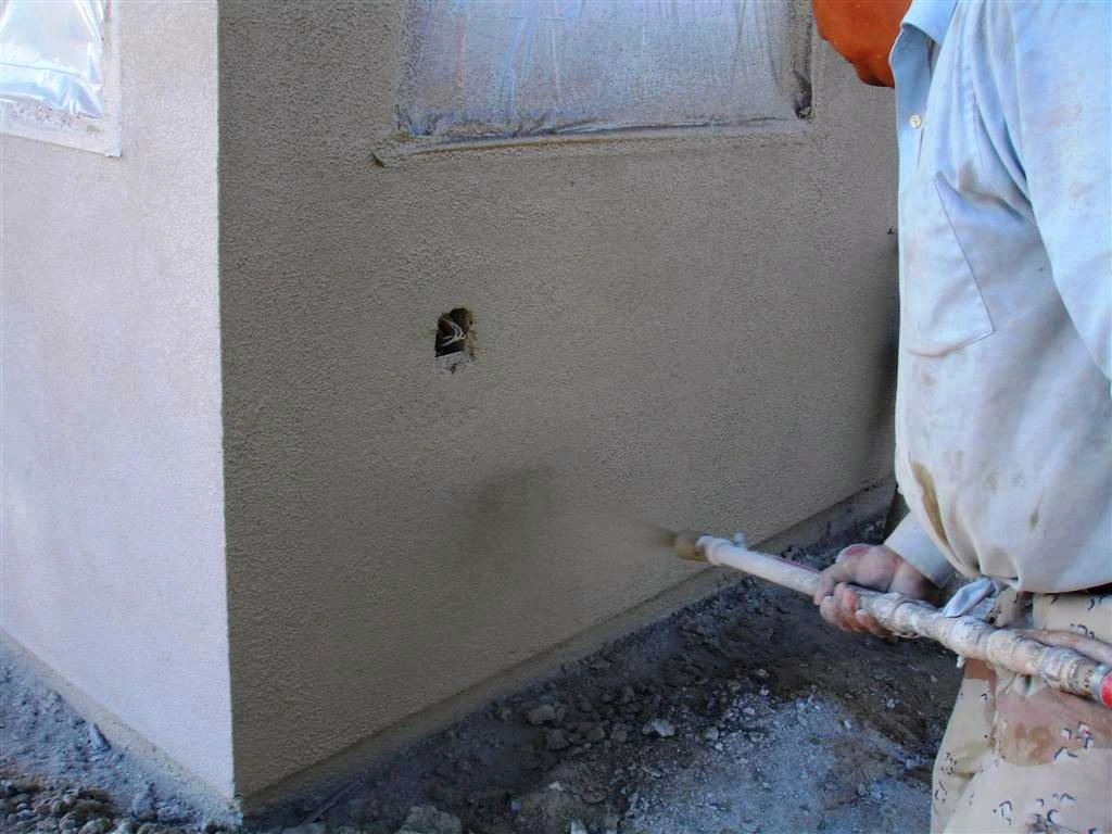 A man is using a hammer to apply paint to a wall, showcasing a unique approach to home improvement.